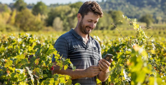 Imagem de um homem usando um smartphone em meio a uma plantação verde