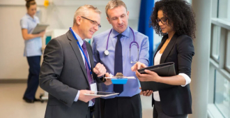 Imagem de um médico, um homem administrador e uma mulher administradora conversando